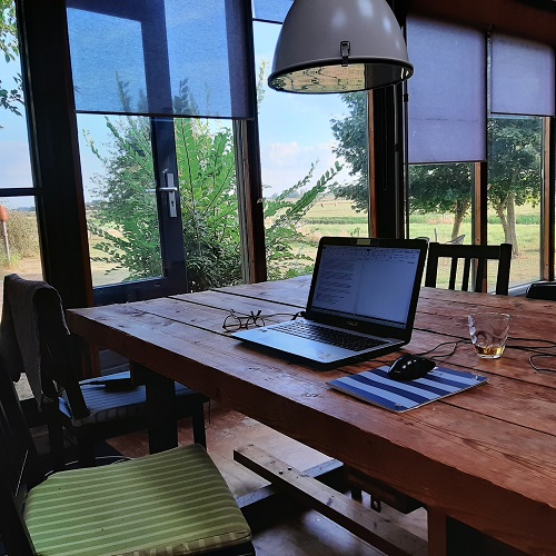 Laptop auf einem Holztisch mit Blick nach draußen in die Landschaft