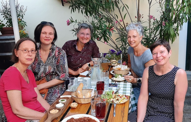 fünf Frauen sitzen im Freien an einem Tisch und essen