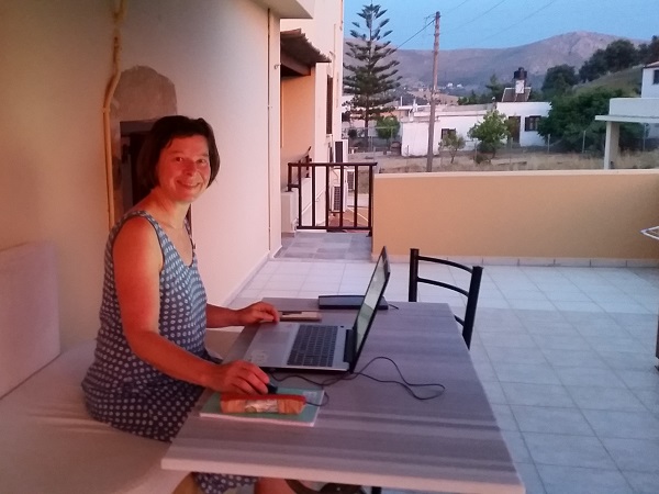 Frau arbeitet auf einer Terrasse auf Kreta an ihrem Laptop