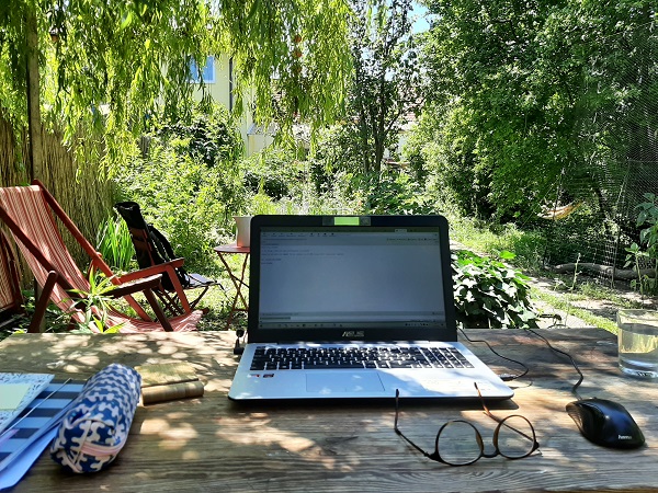 Arbeitsplatz mit Laptop im Garten unter einer Weide