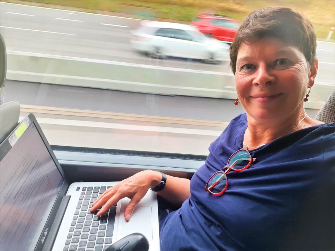 Frau arbeitet im Bus an einem Laptop