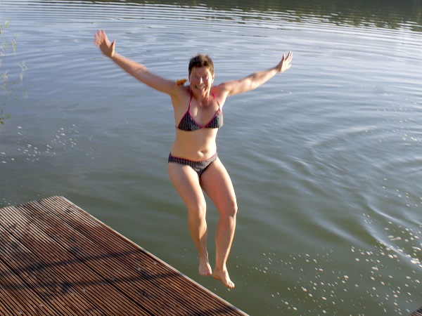 Frau springt vom Steh aus in einen See