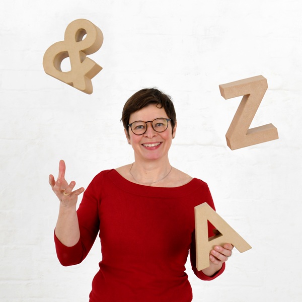 Kerstin Salvador jongliert mit großen Pappbuchstaben – ein Bild für ihre Freude an Sprache und die Geschichte hinter ihrem Claim „Duden an die Freude“.