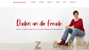Kerstin Salvador sitzt auf einem Bücherstapel vor einem hellen Hintergrund. Neben ihr liegen und stehen große Pappbuchstaben. Im Bild steht der Claim „Duden an die Freude“.